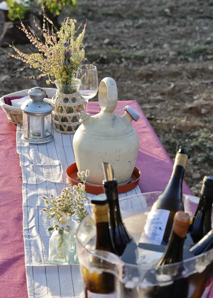 Flores, copas y botellas preparadas sobre una mesa en la finca